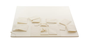 Precise three-dimensional paper reconstruction of a workspace by Herbert Stattler, showing desk objects as monochromatic white paper models based on original pencil drawings.